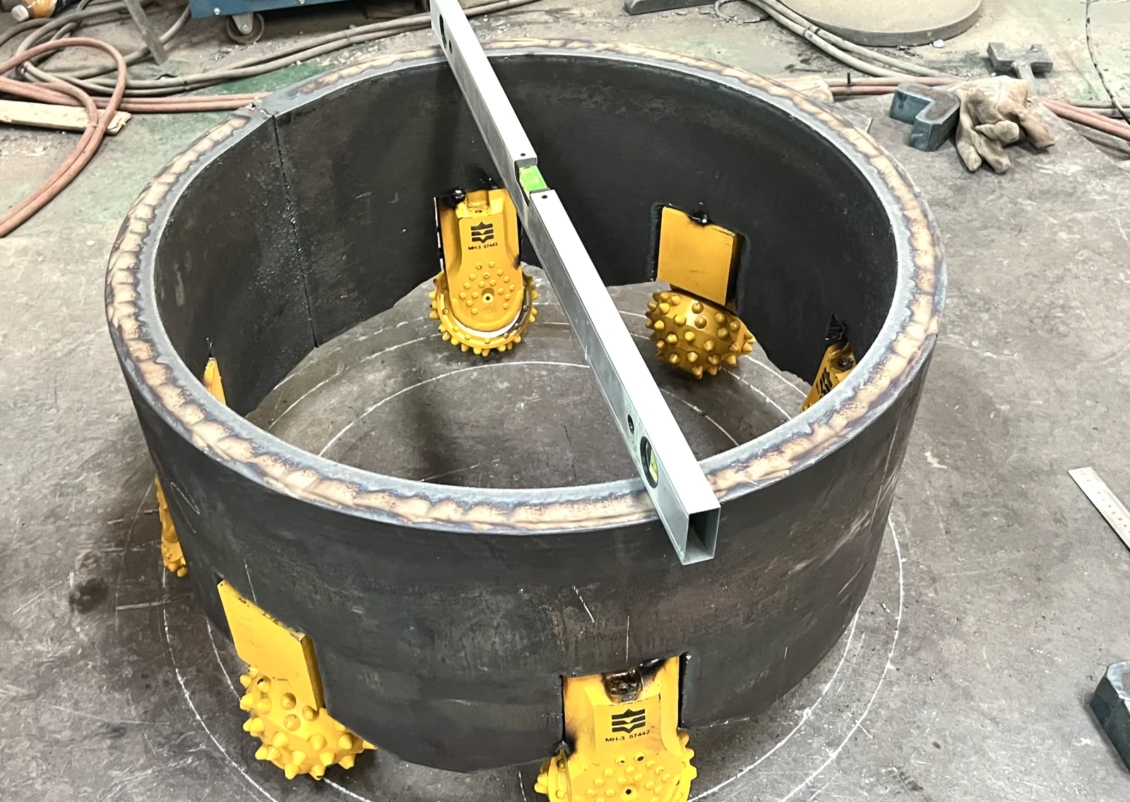 Roller bits checked on a marked steel-plate layout