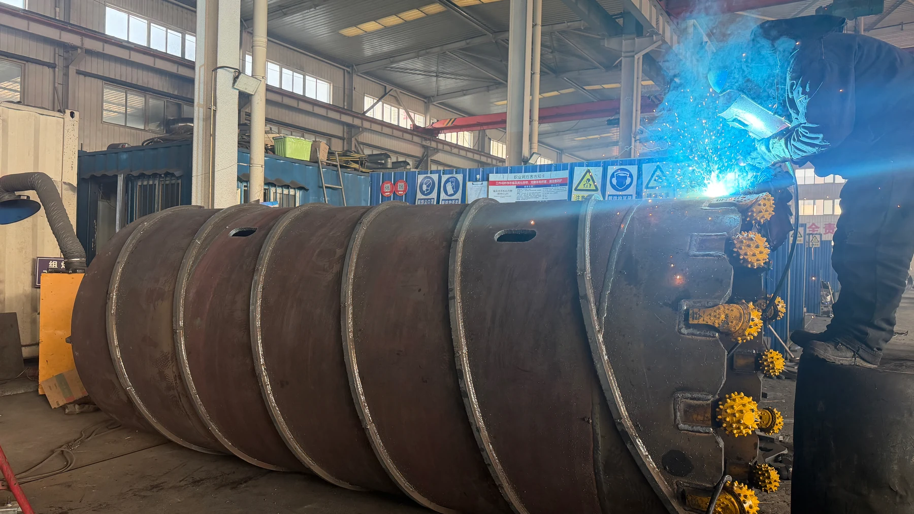 Welder working at the cutting end of a roller-bit core barrel in the workshop