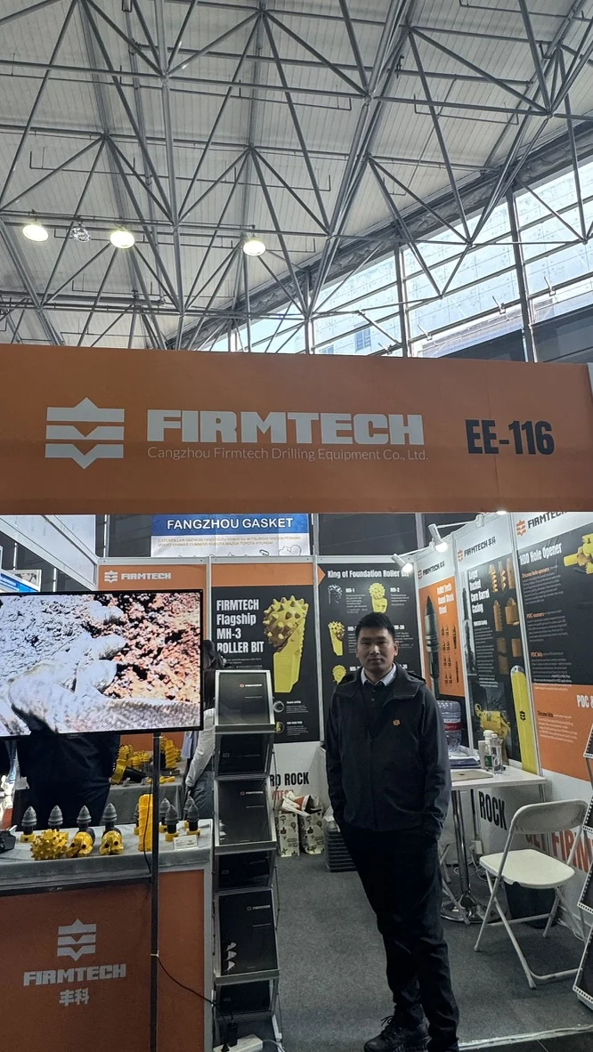 At the FIRMTECH booth, with the MH-3 roller-bit display in the background.