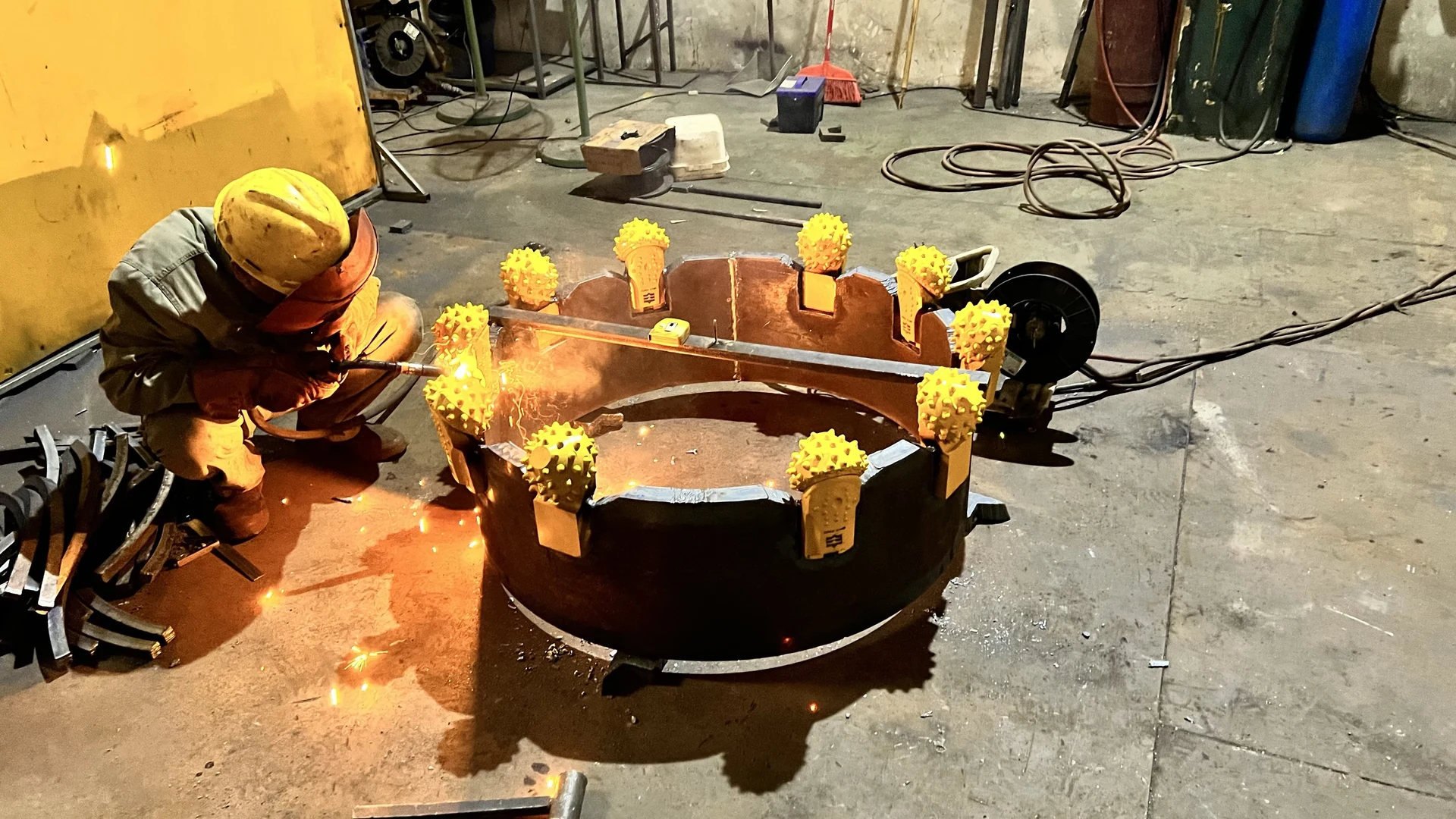 Welder working on a cutting ring fitted with yellow roller bits
