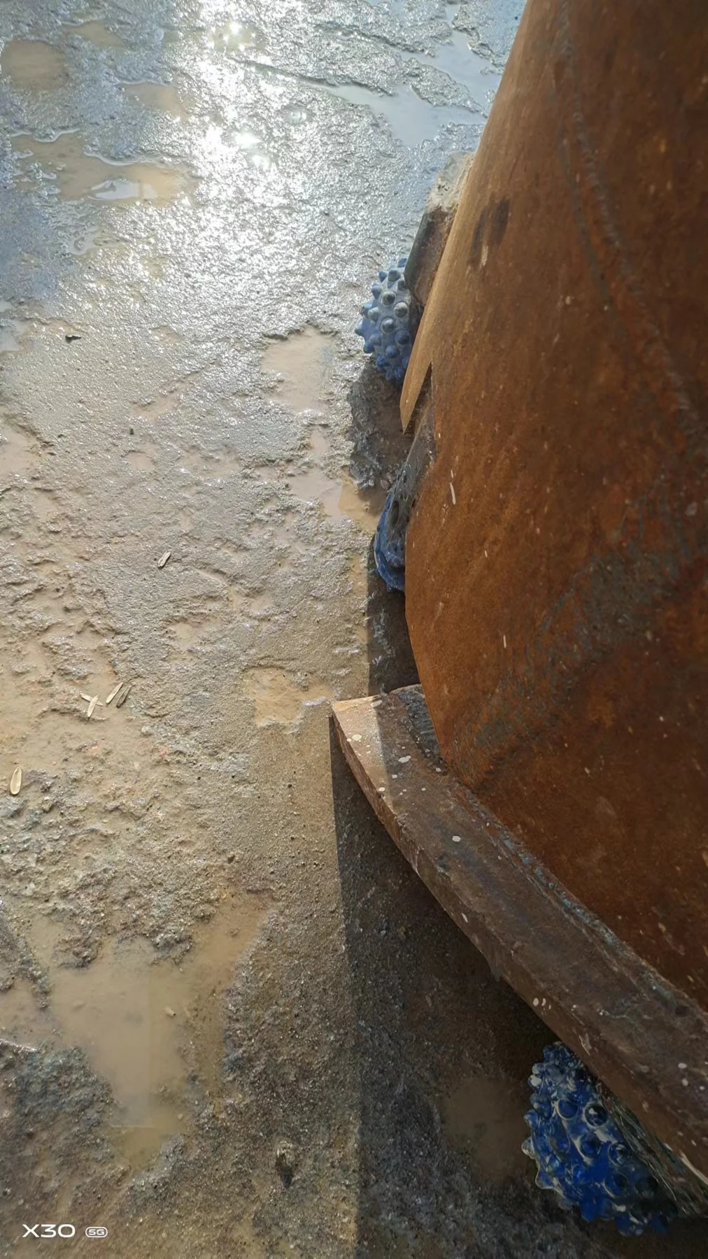 Side view of a core barrel showing an external guide strip and nearby roller bits